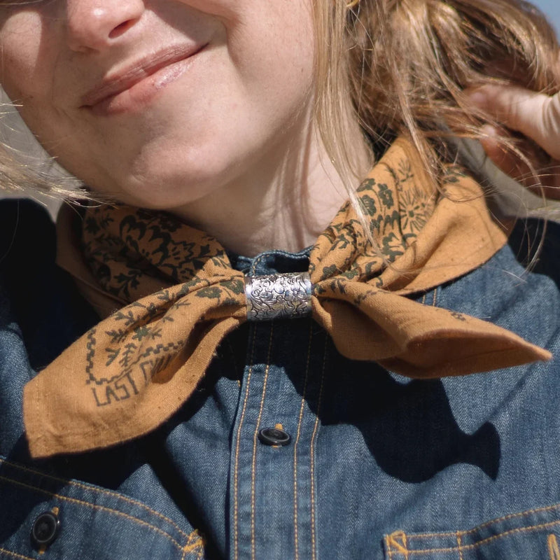 Woman wearing a floral bandana by Last Chance Textiles with a denim shirt, styled with a silver scarf ring at LADDER.