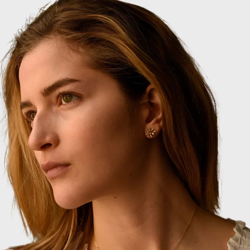 Woman wearing Sunburst earrings from LADDER, by 8.6.4, in a close-up editorial portrait.