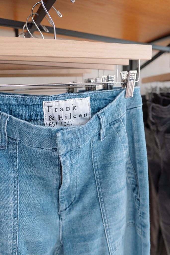 Blue jeans hanging on a rack with 'Frank & Eileen' label.